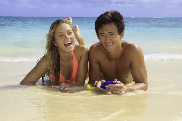 Пара на пляже на Гавайях с сотовым телефоном — стоковое фото