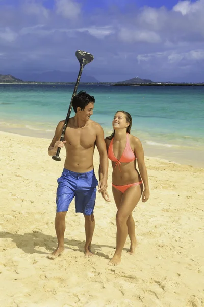 Casal andando na praia com sua raquete — Fotografia de Stock