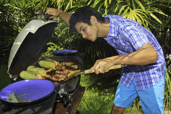 Asian man cooking on an outdoor grill