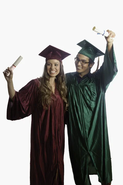 Graduados em boné e vestido com diplomas — Fotografia de Stock