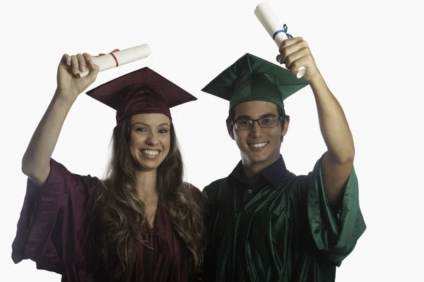 Graduates in cap and gown with diplomas Stock Picture