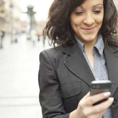 Businesswoman with smartphone walking on street clipart