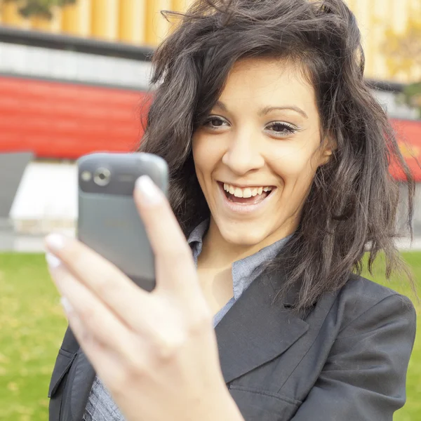 Ung kvinna med roliga hår leende med hjälp av mobiltelefon promenader — Stockfoto