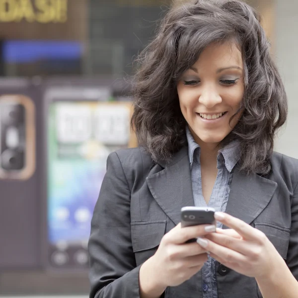 Jonge vrouw met behulp van mobiele telefoon op straat lopen — Stockfoto