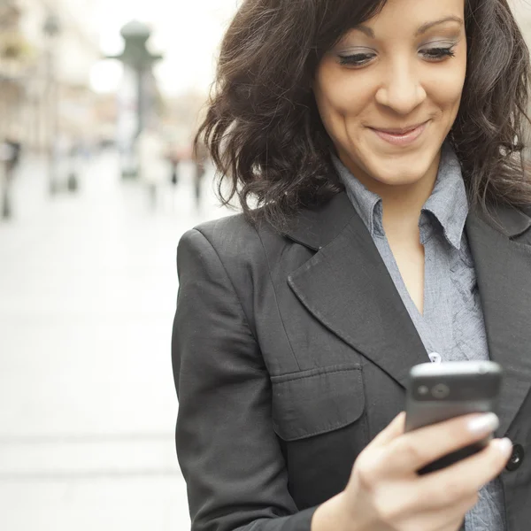 Zakenvrouw met smartphone lopen op straat — Stockfoto