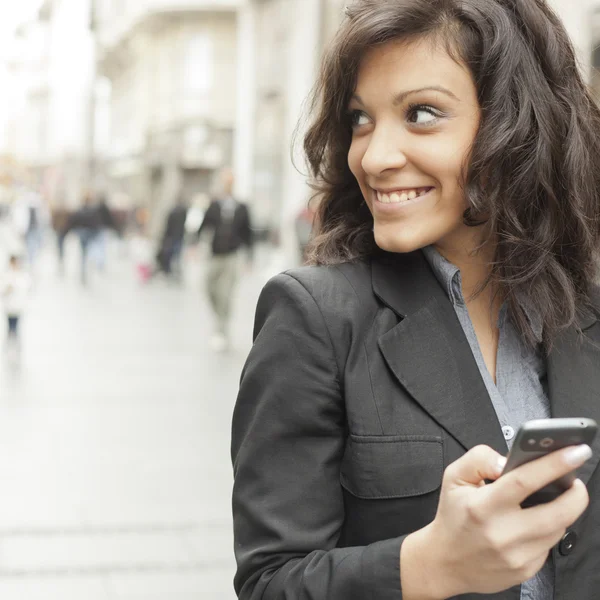 Genç kadın ile sokakta yürürken smartphone — Stok fotoğraf