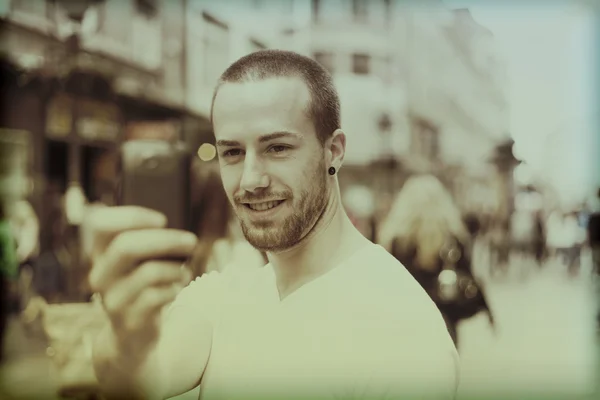 Χαμογελαστός τύπος στο δρόμο φωτογραφίζοντας με το κινητό τηλέφωνο — Φωτογραφία Αρχείου