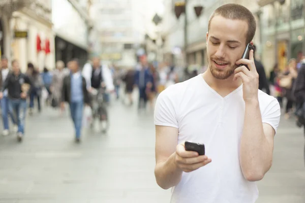 Mluvení na jednom mobilním telefonu a v ruce drží secund buňky — Stock fotografie