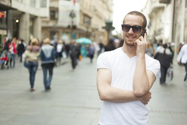 Güneş gözlüğü ve cep telefonu ile genç adam — Stok fotoğraf