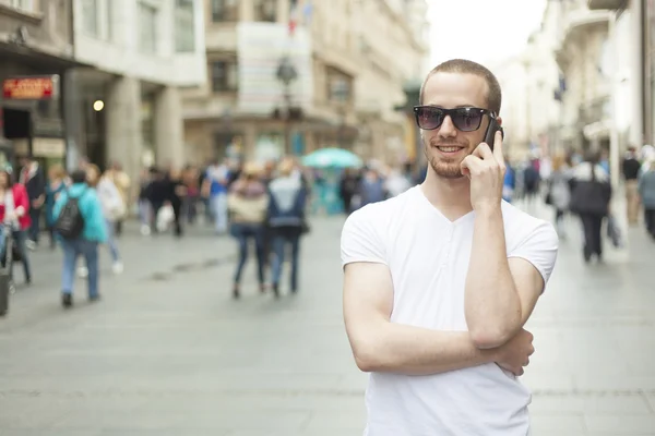 Homme avec lunettes de soleil et téléphone portable marche — Photo
