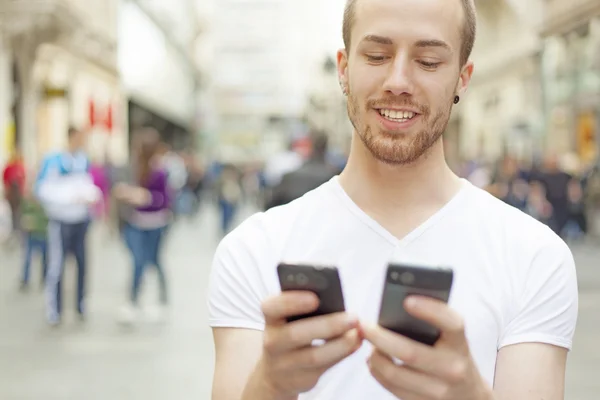 Hombres sonrientes mirando en dos móviles - ¿Qué es mejor ? —  Fotos de Stock