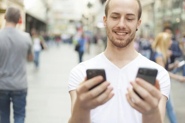 Man met twee telefoons - wat mobiele telefoon is beter? — Stockfoto