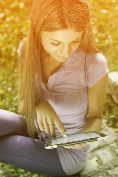 Krásná žena s tabletovým počítačem v parku — Stock fotografie