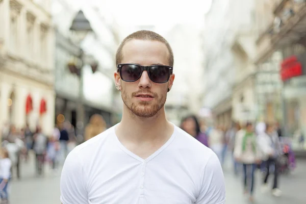 Homem na rua em camisa branca e óculos escuros — Fotografia de Stock