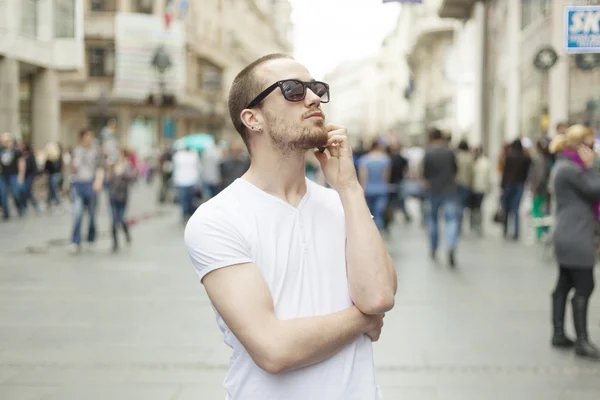 Hombre joven con gafas de sol y teléfono celular caminando — Foto de Stock