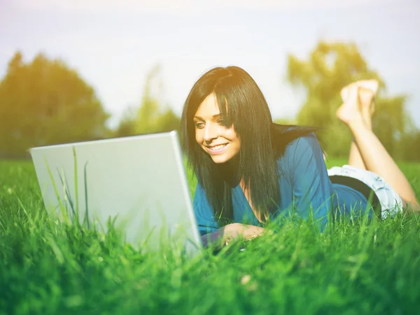 Mujer joven usando el ordenador portátil en el parque — Foto de Stock