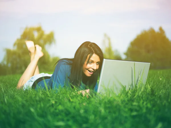 Ung kvinna som använder laptop i parken — Stockfoto