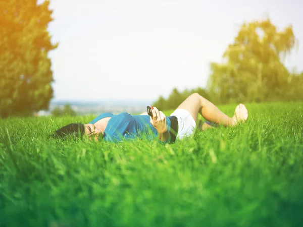 Young woman using mobile phone in park — Stock Photo, Image