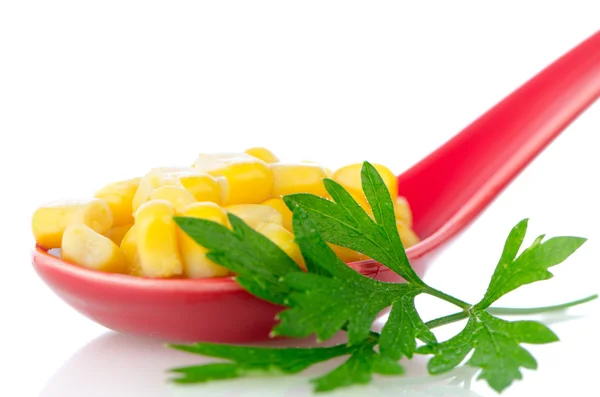 Canned corn in a red ceramic spoon — Stock Photo, Image