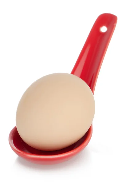 Huevo marrón en una cuchara de cerámica roja — Foto de Stock