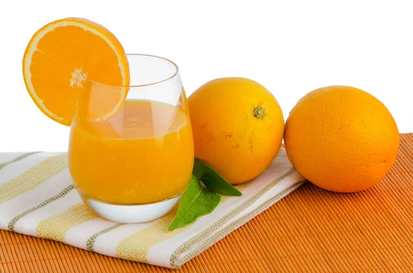 Szklanka soku pomarańczowego i świeżych pomarańczy — Zdjęcie stockowe