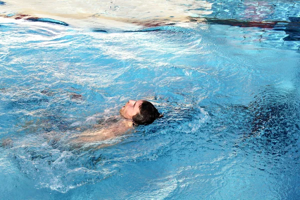 Молодой человек учится плавать на спине — стоковое фото