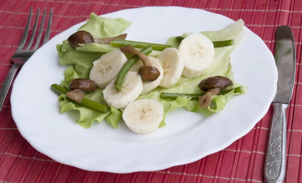 Creatieve salade van gebakken schimmels en stengels van knoflook en zoete bananen — Stockfoto