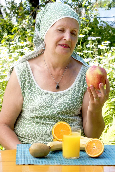 De volwassen vrouw in een zomertuin met smakelijk vers rijp fruit — Stockfoto