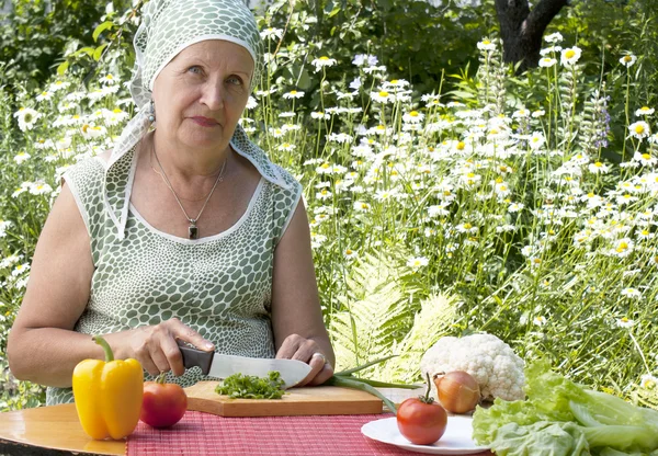 De gelukkige vrouw snijdt salade — Stockfoto