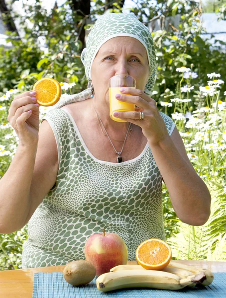La mujer adulta feliz bebe jugo de naranja fresco — Foto de Stock