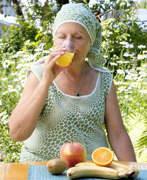 La mujer adulta bebe jugo de naranja fresco — Foto de Stock