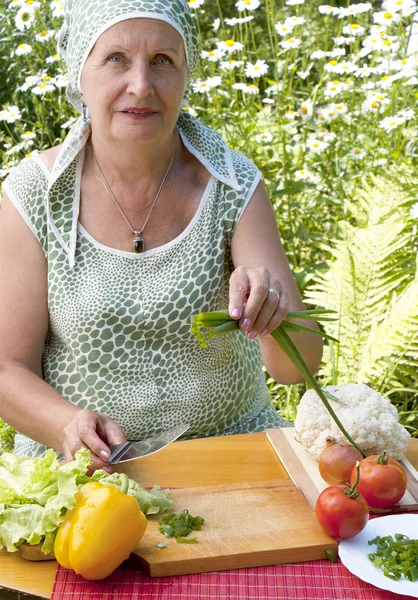 Die erwachsene Frau schneidet Salat — Stockfoto