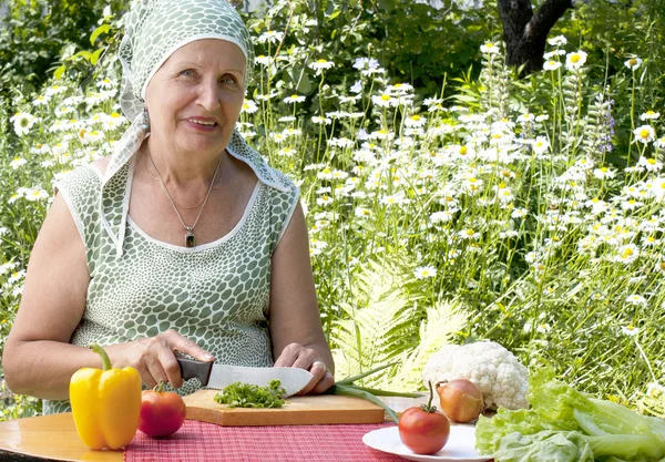 Bir gülümseme ile yetişkin kadın salata keser — Stok fotoğraf