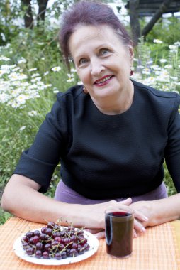 The happy smiling woman and ecologically pure berries of a cherry