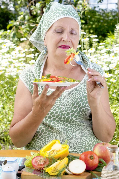Aikuinen nainen syö herkullisia tuoreita vihanneksia — kuvapankkivalokuva