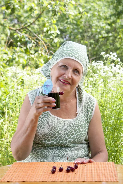 A mulher sorridente feliz bebe suco de cereja fresco — Fotografia de Stock