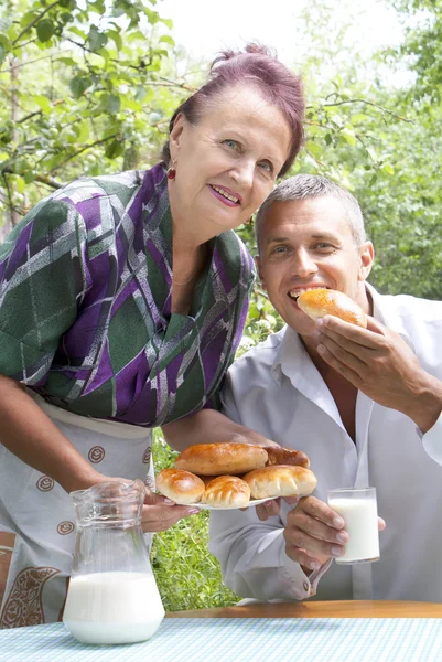 De gelukkige familie eet gebakken huis taarten met verse melk — Stockfoto