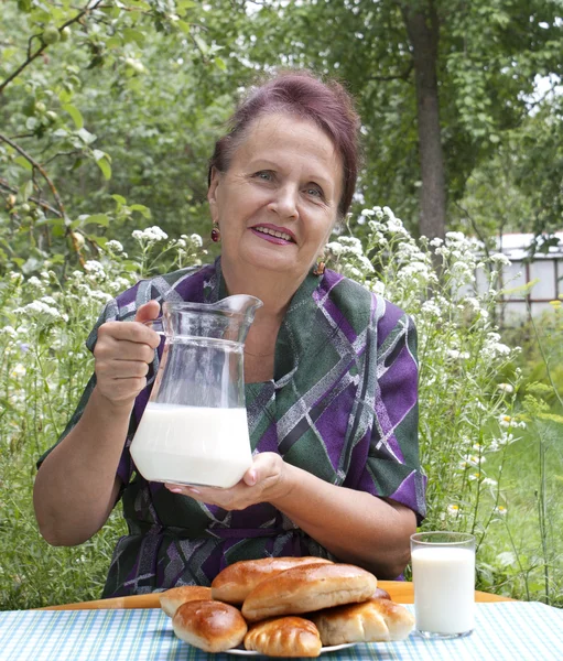 La hembra adulta y apetitosos pasteles de casa horneados con leche fresca — Foto de Stock