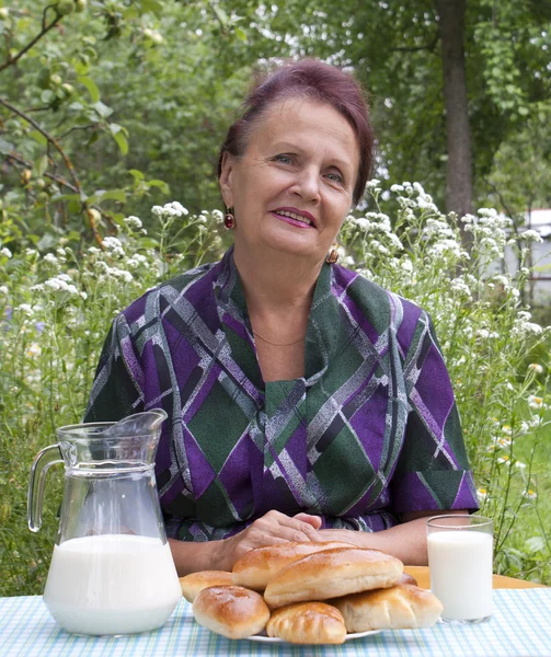 Die erwachsenen weiblichen und appetitlich gebackenen Hauskuchen mit frischer Milch — Stockfoto