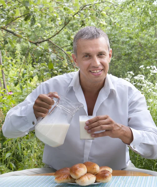 Der erwachsene Mann und appetitlich gebackene Hauskuchen mit frischer Milch — Stockfoto