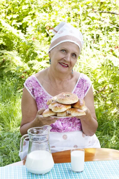 Взрослая женщина и аппетитные домашние пироги со свежим молоком — стоковое фото