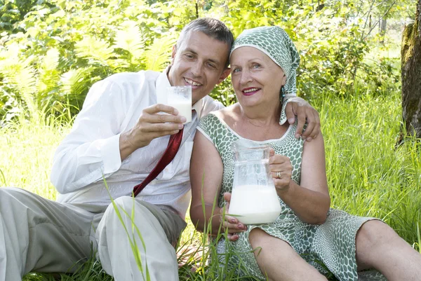 Счастливая женщина пьет парное молоко в летнем саду — стоковое фото