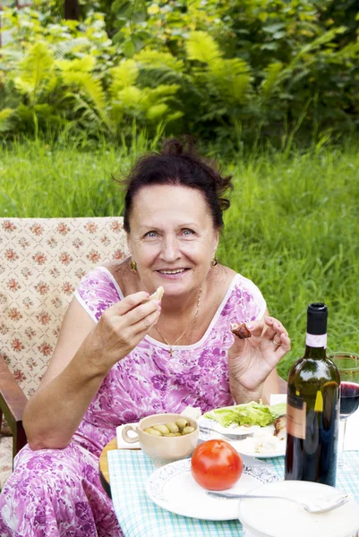 The adult woman has dinner in a summer green garden — Φωτογραφία Αρχείου