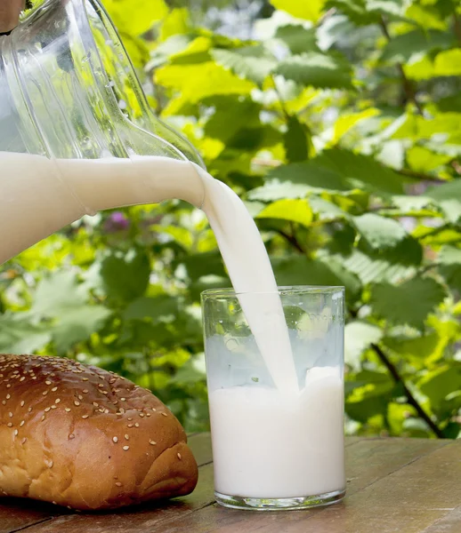 Verse glas melk en brood op houten tafel — Stockfoto