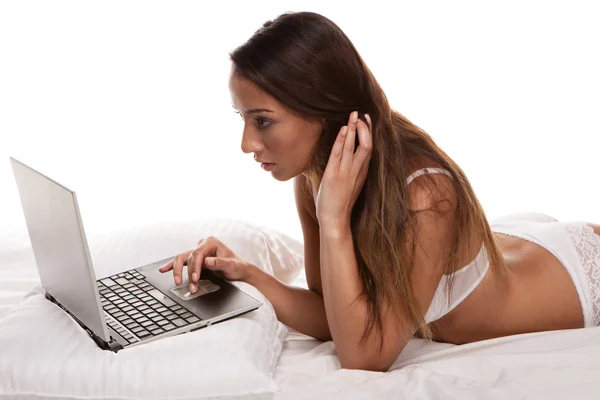 Jolie brune au lit avec un ordinateur portable — Photo