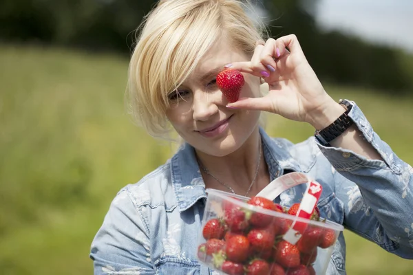 Schöne blonde Frau pflückt Erdbeeren — Stockfoto