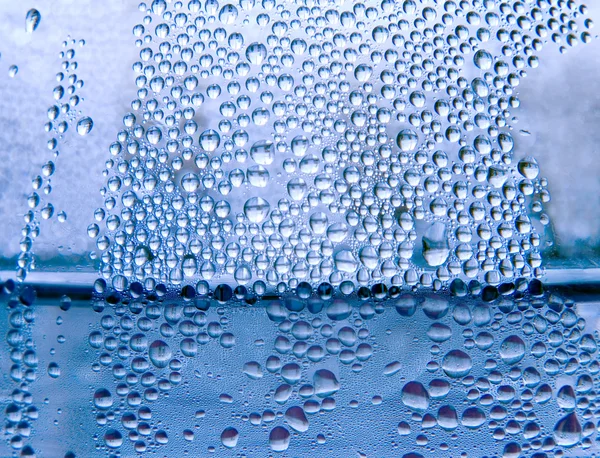 Waterdruppels op een transparante glazen oppervlak. — Stockfoto
