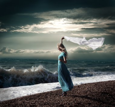 fırtınalı denizde uzun elbiseli sarışın kadın