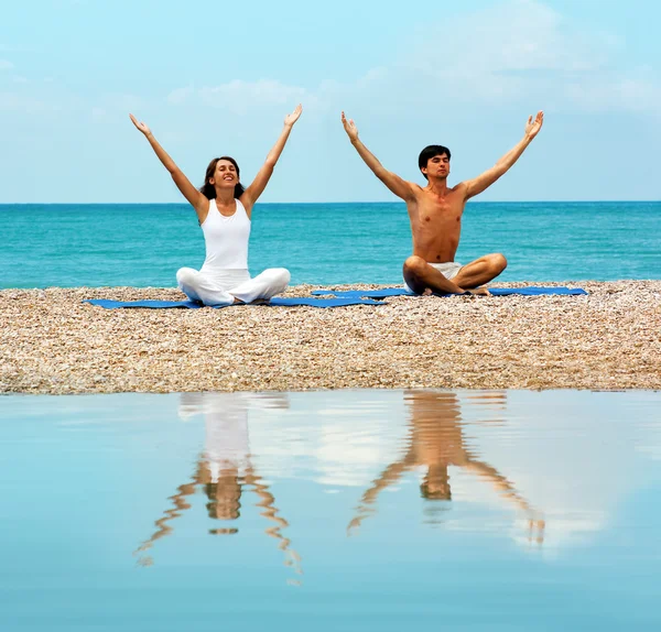 Pareja en la playa practicando yoga — Foto de Stock