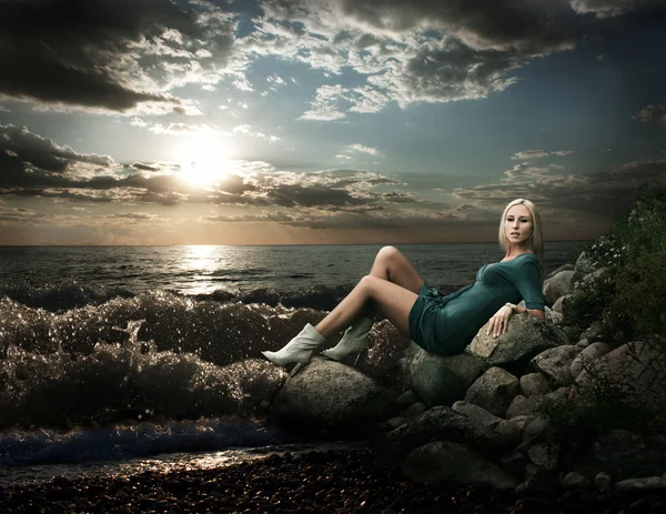Блондинка, сидящая у моря — стоковое фото